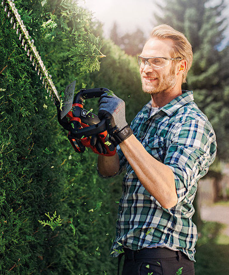 man with a cordless hedge trimmer