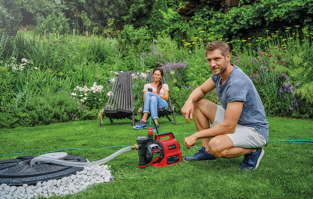 A man kneeling and a woman sitting next to a smart garden pump.