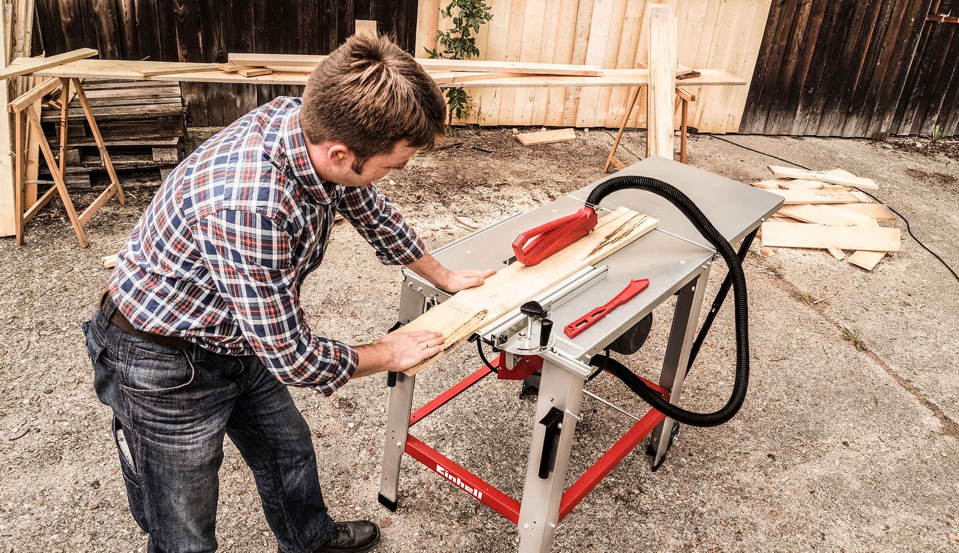 A man using the parallel guide on a table saw to cut a wooden panel.